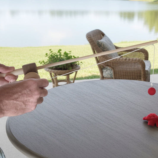 Grandpa teaches child to fish with toy wooden fishing pole and fabric fish