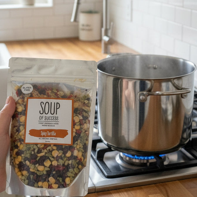 Packaged soup mix held by a person on a stone surface
