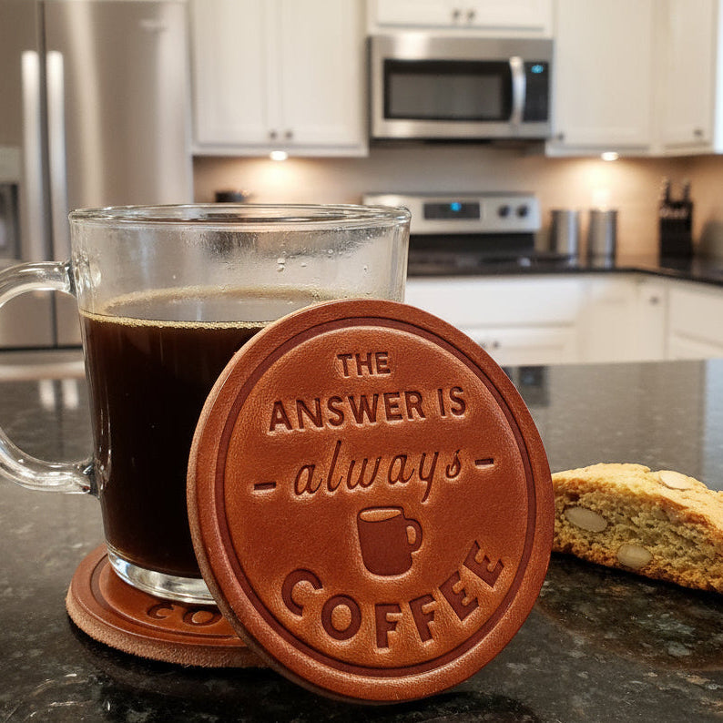 Clear mug of coffee on leather coffee-embossed coaster