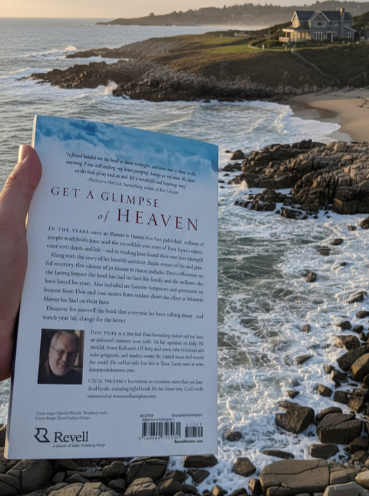 Person holding a book titled 'Get a Glimpse of Heaven' by a coastal landscape with waves and rocks.