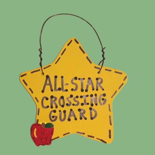 Yellow star-shaped sign with 'All Star Crossing Guard' text and an apple on a white background