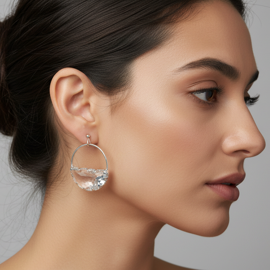 Gold hoop earrings with clear crystal stones on a gray background