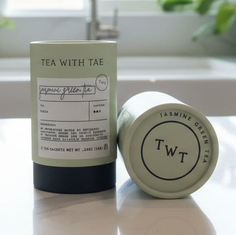 Two cylindrical containers labeled 'Tea with Tea' on a wooden surface.