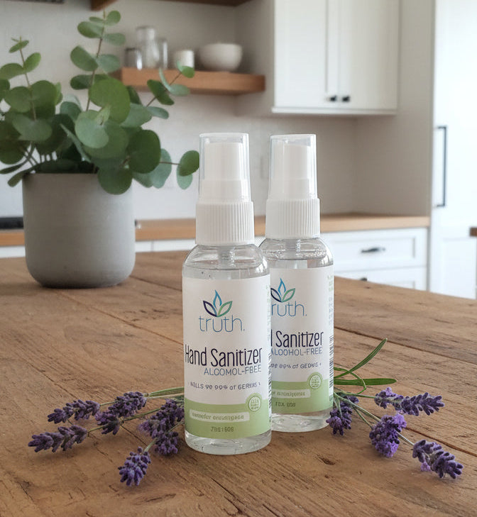 Two bottles of hand sanitizer on a dark surface with a blurred background