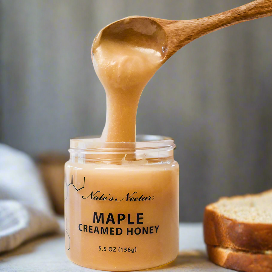 Jar of Maple Creamed Honey with a wooden spoon lifting some honey